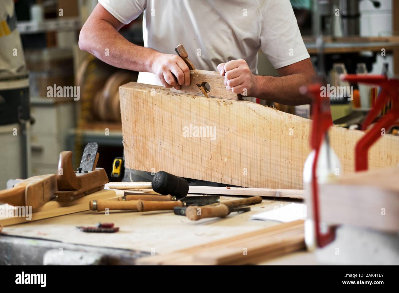 Tischler Hobel ein Stück Holz mit einem Hobel die Kante in der Holzbearbeitung Workshop in einer Nahaufnahme auf Tools in der Bank zu glätten, seine Hände und shavin Stockfoto