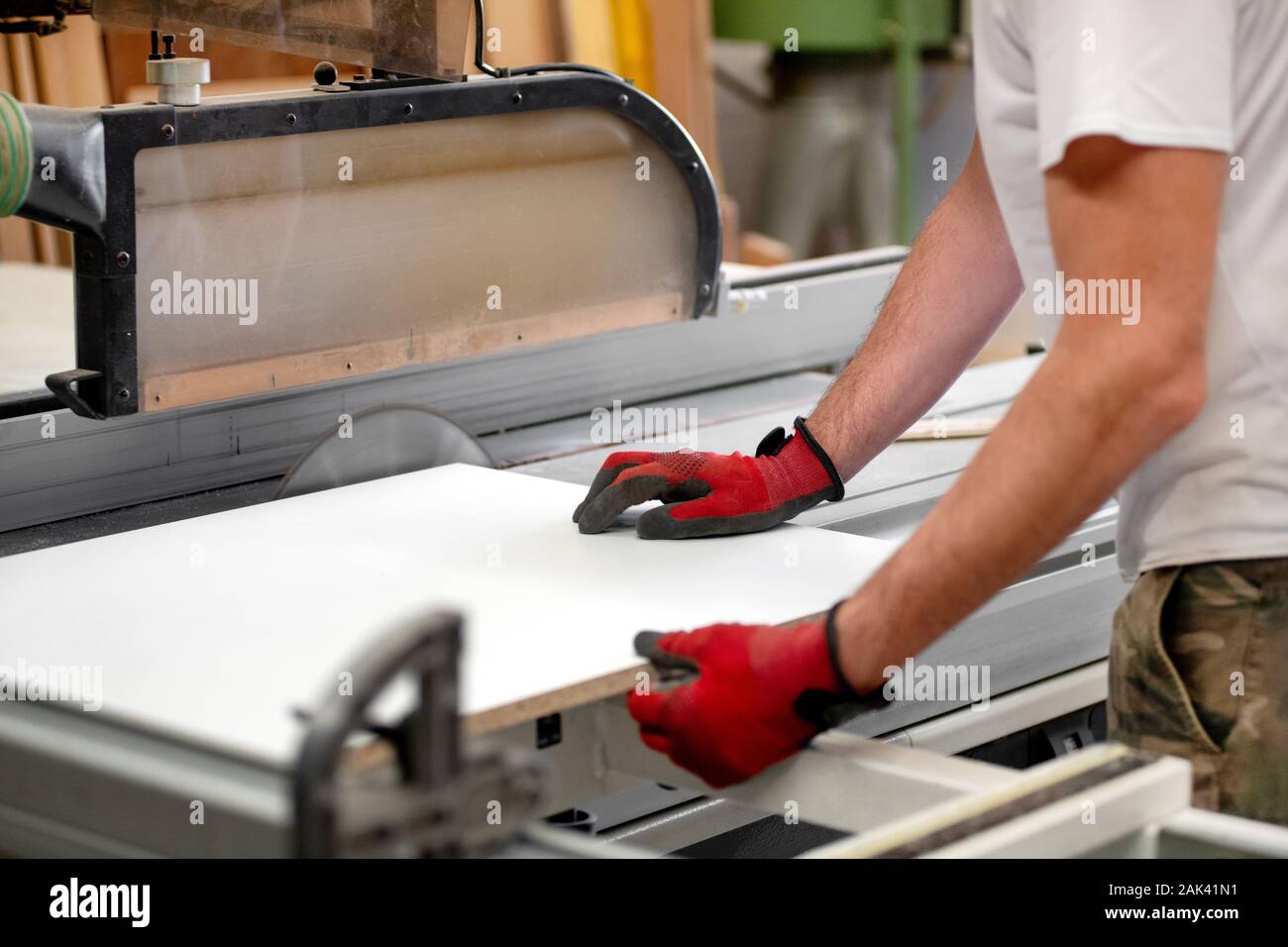 Tischler sägen ein Brett auf einer Kreissäge in Nahaufnahme auf seinem behandschuhten Händen das Holz durch die Power Tool Stockfoto