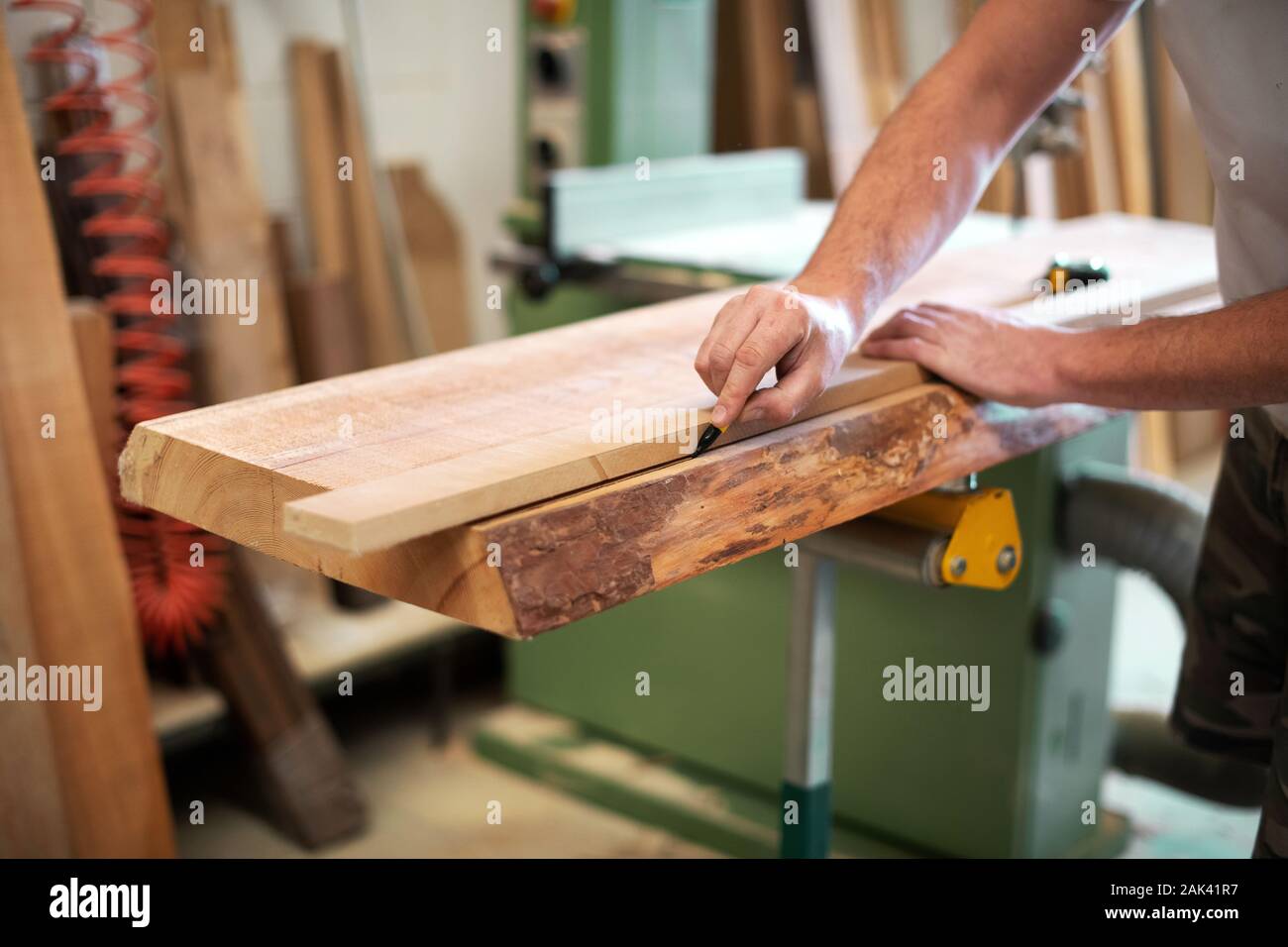 Tischler oder Schreiner mit einem Block Holz, Kennzeichnung mit einem Marker auf einer Werkbank in einem Holzbearbeitung workshop Stockfoto