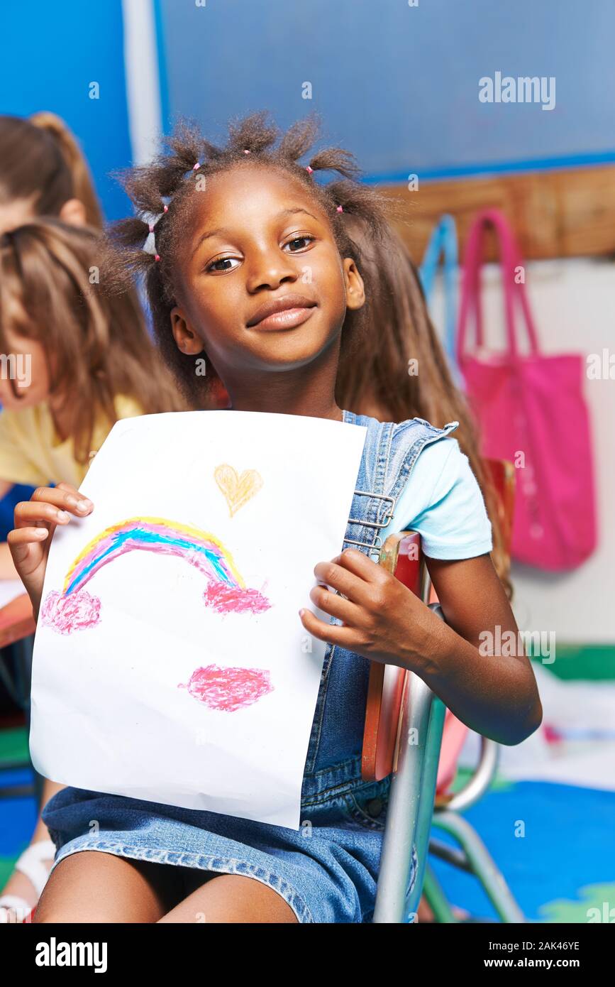 Afrikanisches Mädchen zeigt stolz eine gezeichnete Bild mit Regenbogen Stockfoto