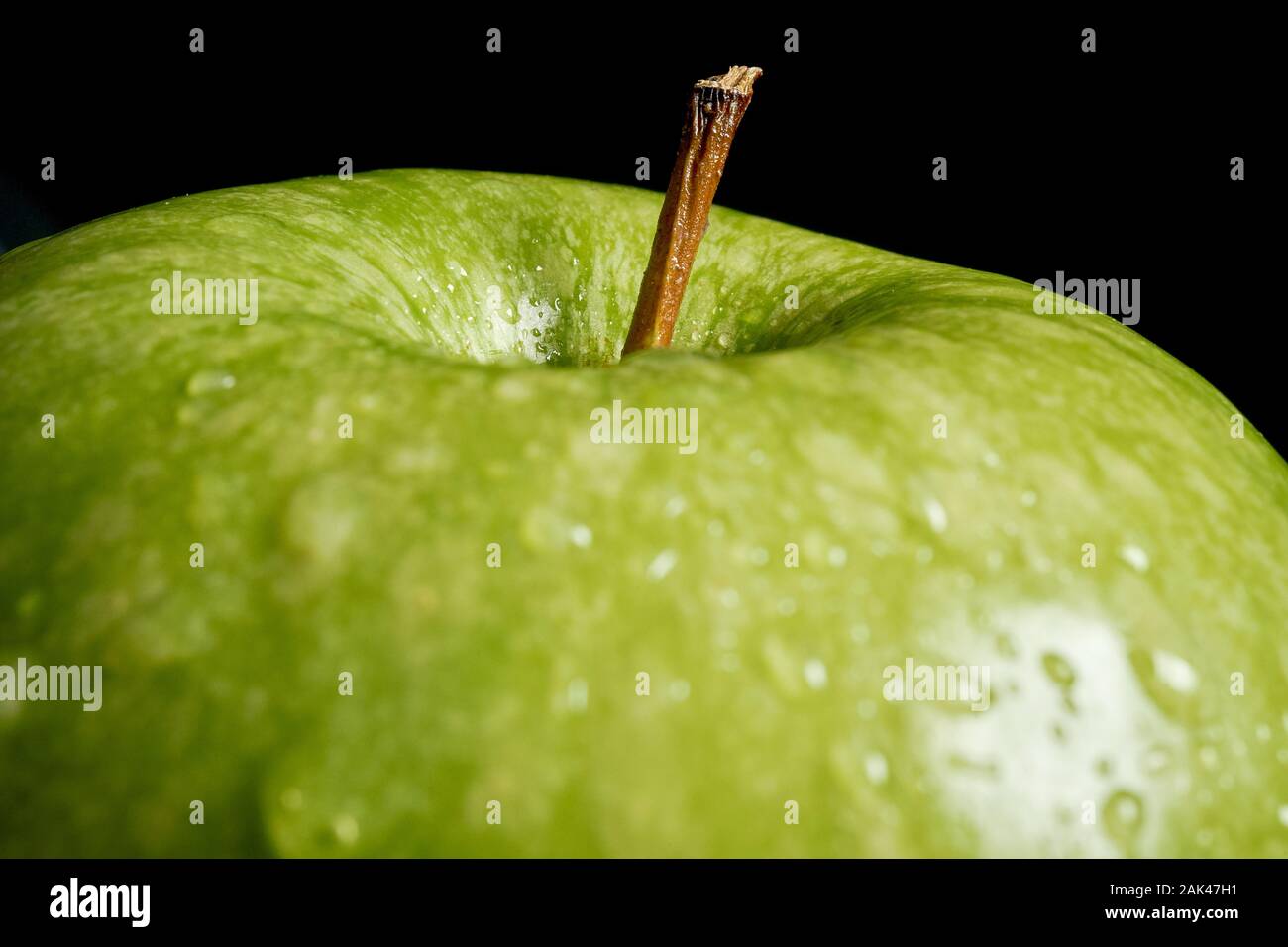 Nahaufnahme von grüner Apfel mit Wassertropfen auf schwarzem Hintergrund Stockfoto