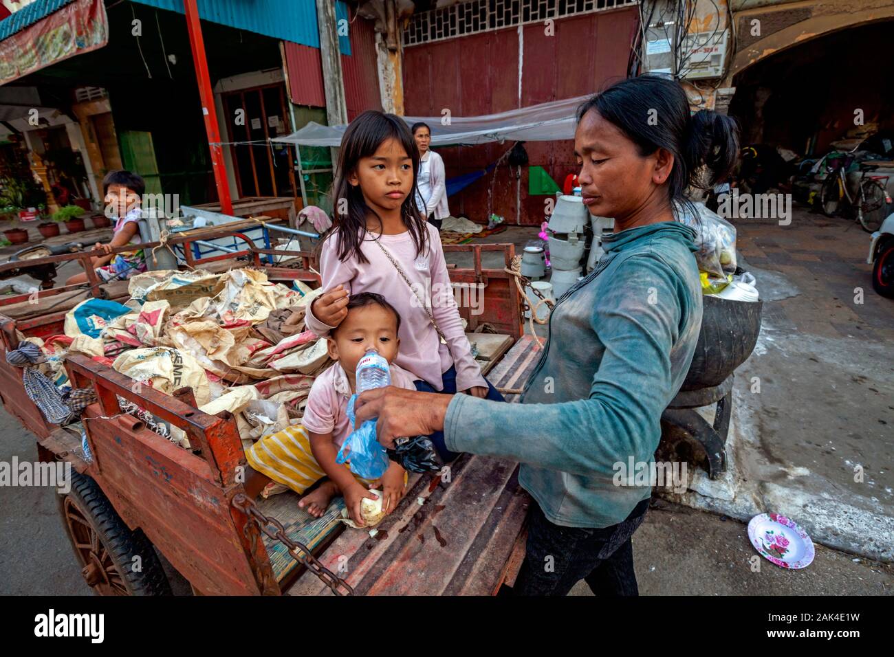 Eine schlechte durstig Toddler, deren Obdachlose Familie scavenges für wieder verwertbare Material Getränke Wasser in einen Warenkorb, Abfalltransporte in Kampong Cham, Kambodscha Stockfoto