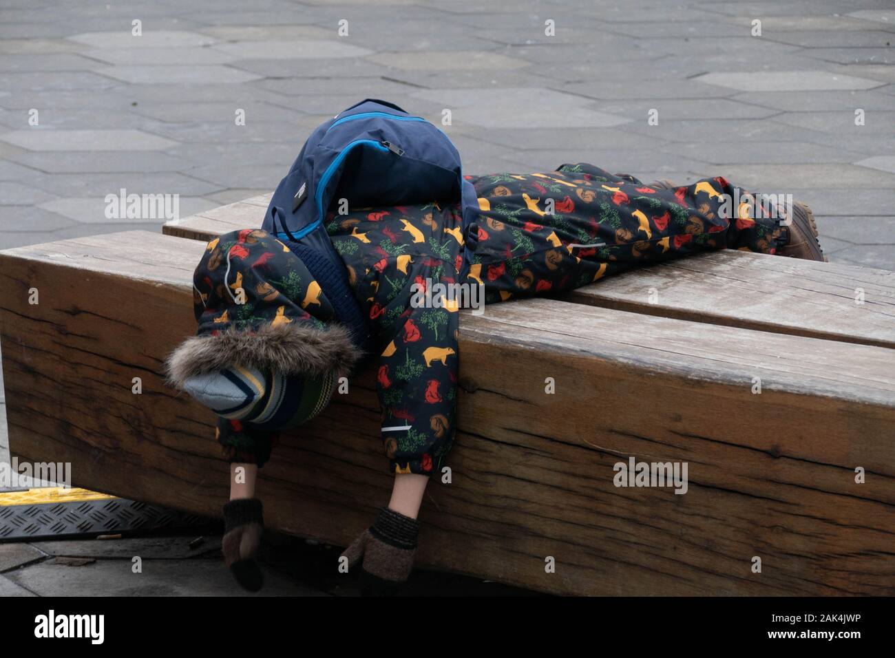 Der Junge liegt mit dem Gesicht nach unten in der Winterkleidung Stockfoto