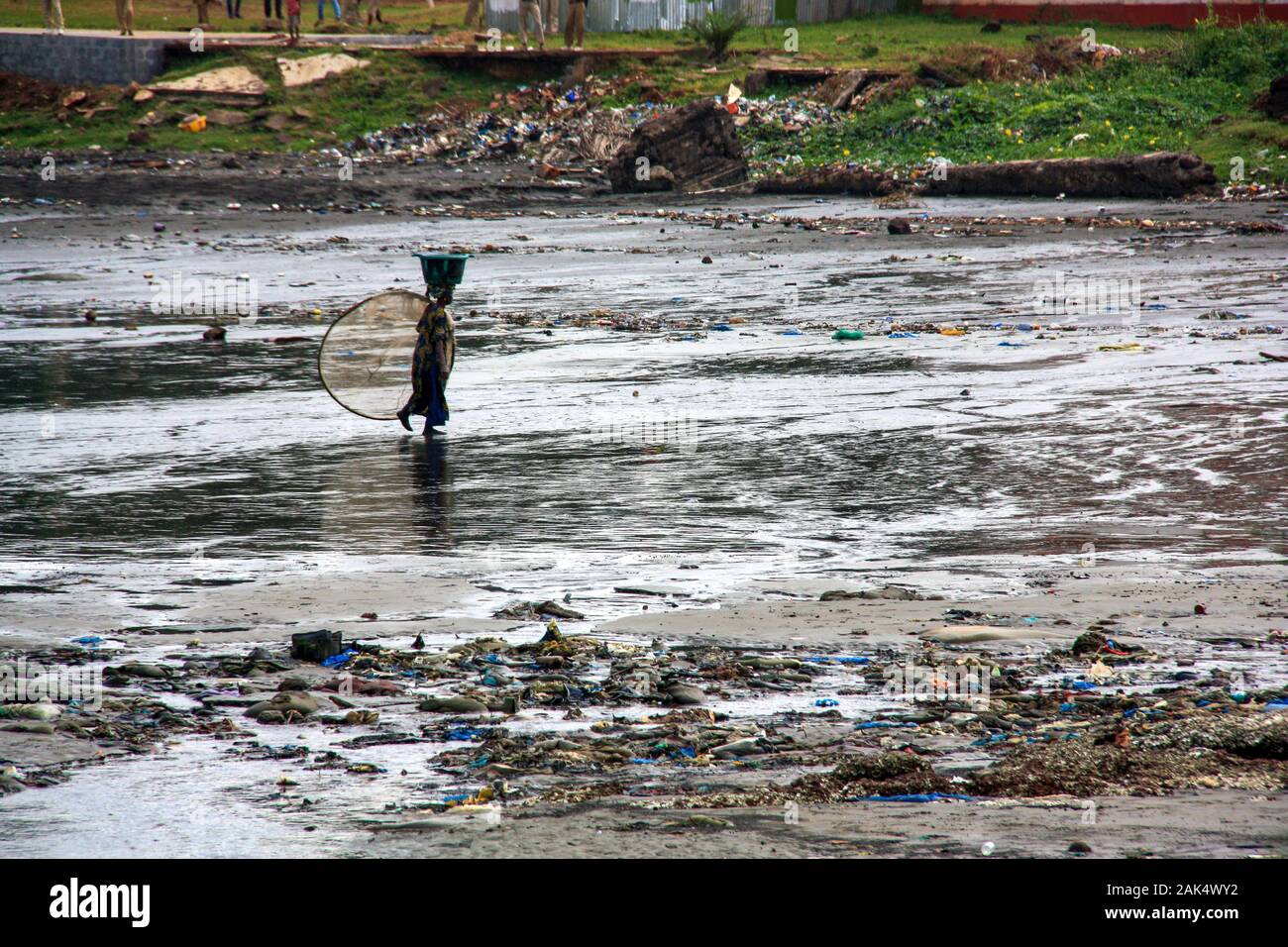 Lokale Fischerin, die aus dem Fischfang im Meer zurückkehrt und den Fang des Tages auf Hear Head, Conakry, Guinea, Westafrika ausgleicht Stockfoto