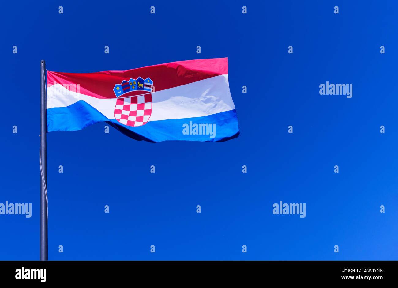Die kroatische Nationalflagge, oder Tricolor, die vollständig gegen einen strahlend blauen Himmel fliegt. Das kroatische Wappen ist deutlich sichtbar Stockfoto