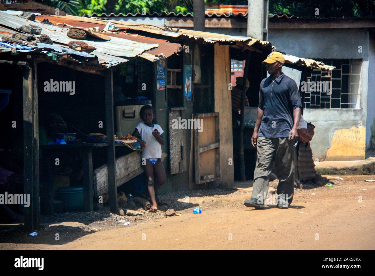 Kleines Kind vor einfachen Geschäften, Geschäften und Restaurants, die von armen Familien in Conakry, Guinea, Westafrika betrieben werden Stockfoto