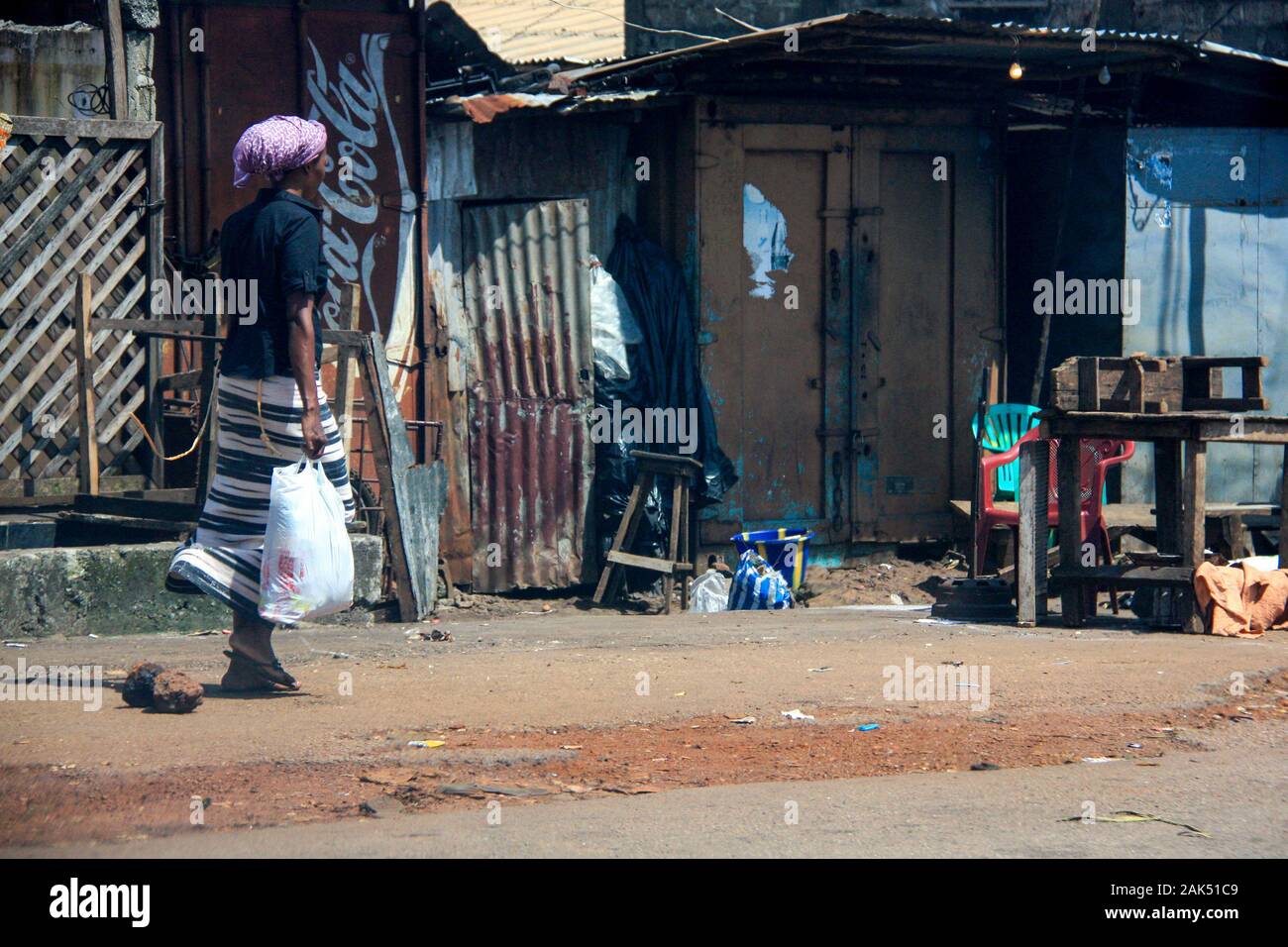 Frau, die auf einer typischen Straße in Conakry, Guinea, Westafrika, spaziert Stockfoto