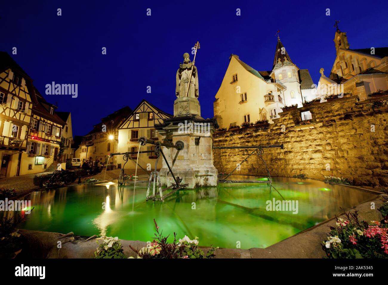 Eguisheim: bei Colmar, Brunnen vor der Weinstraße mit Statue von Papst Leo IX., am Abend, Elsass | Verwendung weltweit Stockfoto