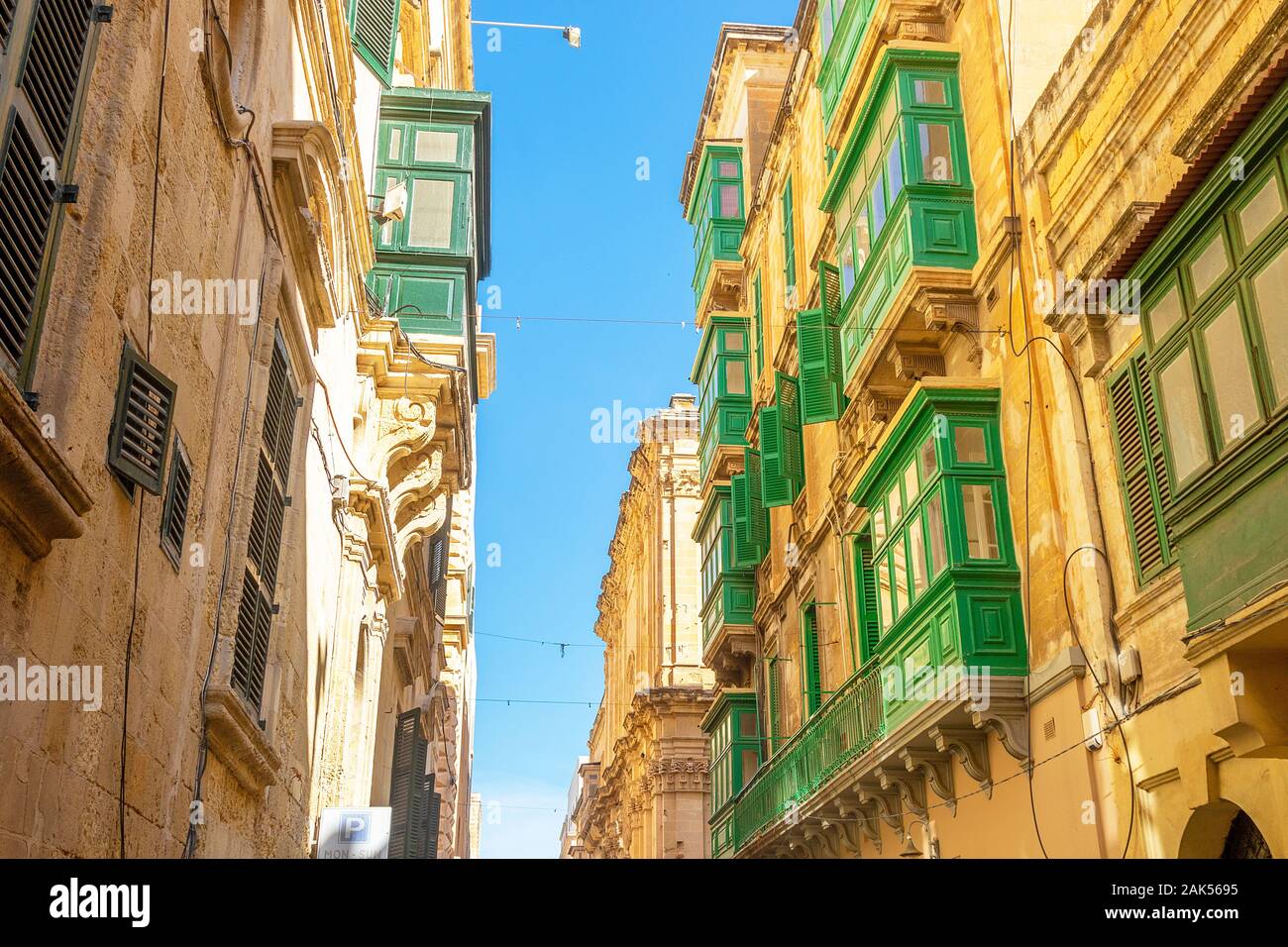 Typischen schmalen maltesischen Straßen mit bunten traditionellen Fenster und Fensterläden aus Holz und Balkone, klaren, blauen Himmel an einem Sommertag, Valletta, Malta Stockfoto