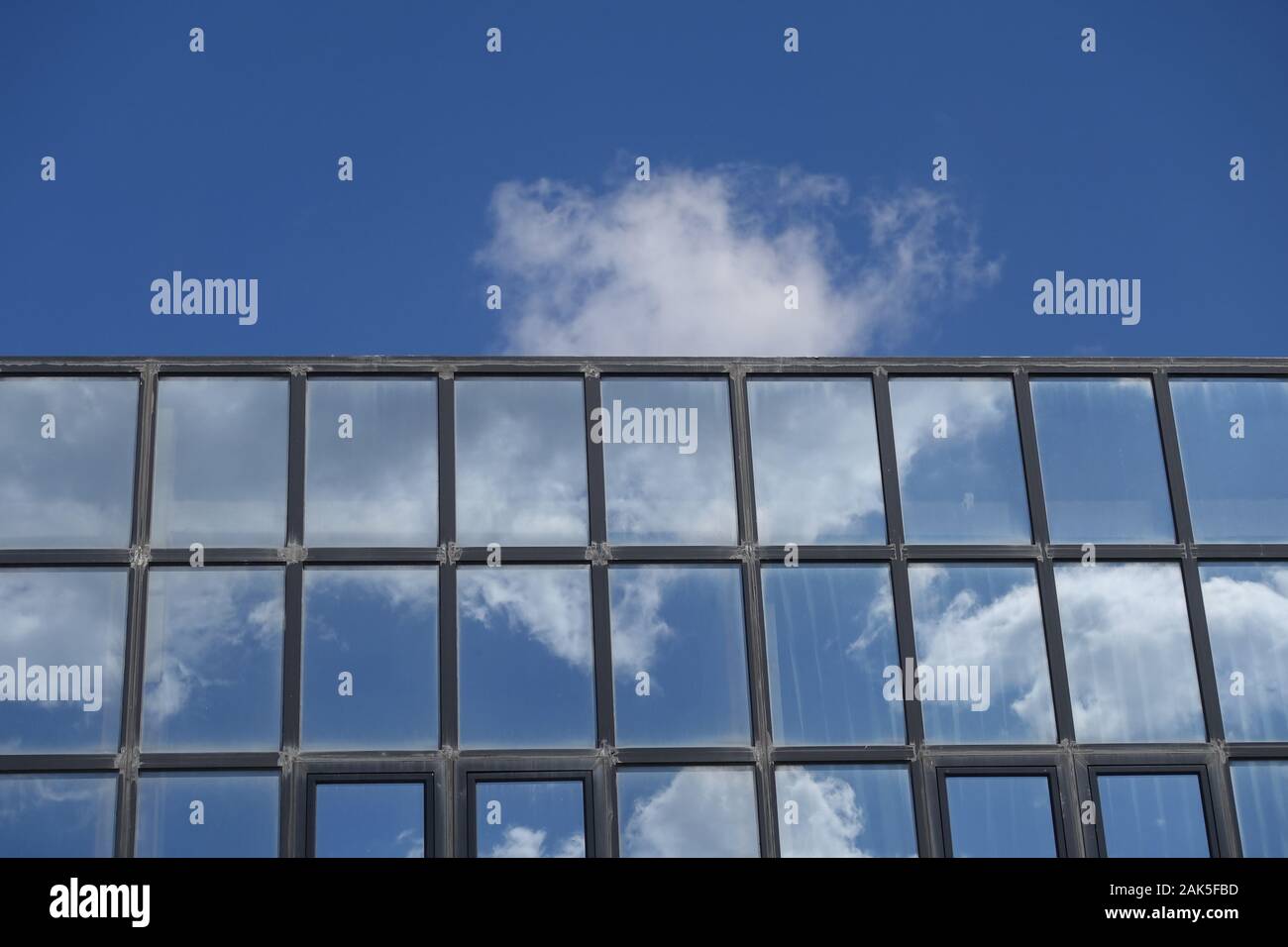 Reflexionen von Wolken und blauer Himmel auf den Aufbau von Windows. Modernen Glasfassade architektonisches Detail. Stockfoto