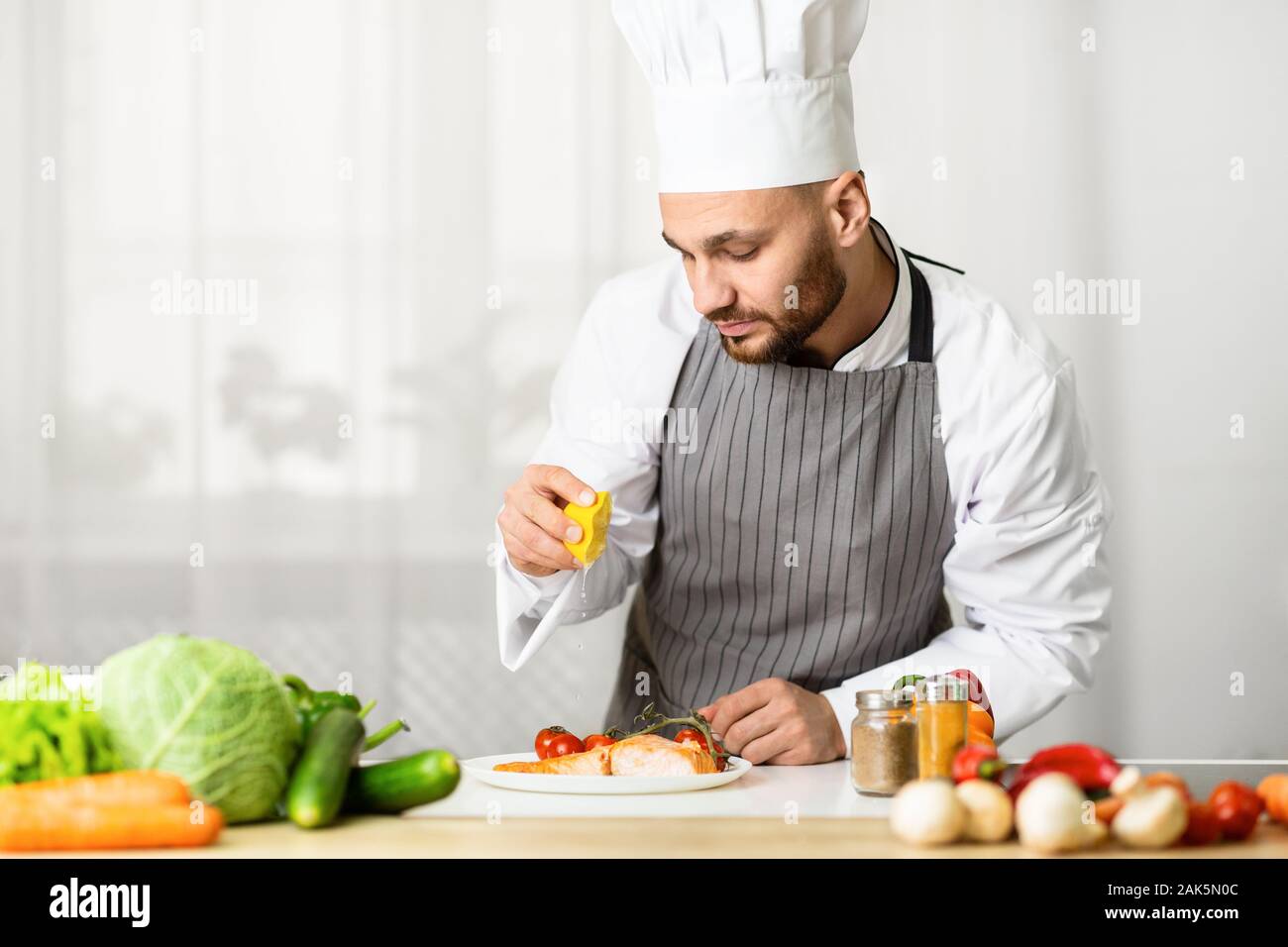 Fisch Rezepte. Männliche Chef quetschen Zitronensaft Auf Gebratenes Lachssteak Plating Teller in der Küche Indoor. Selektiver Fokus Stockfoto