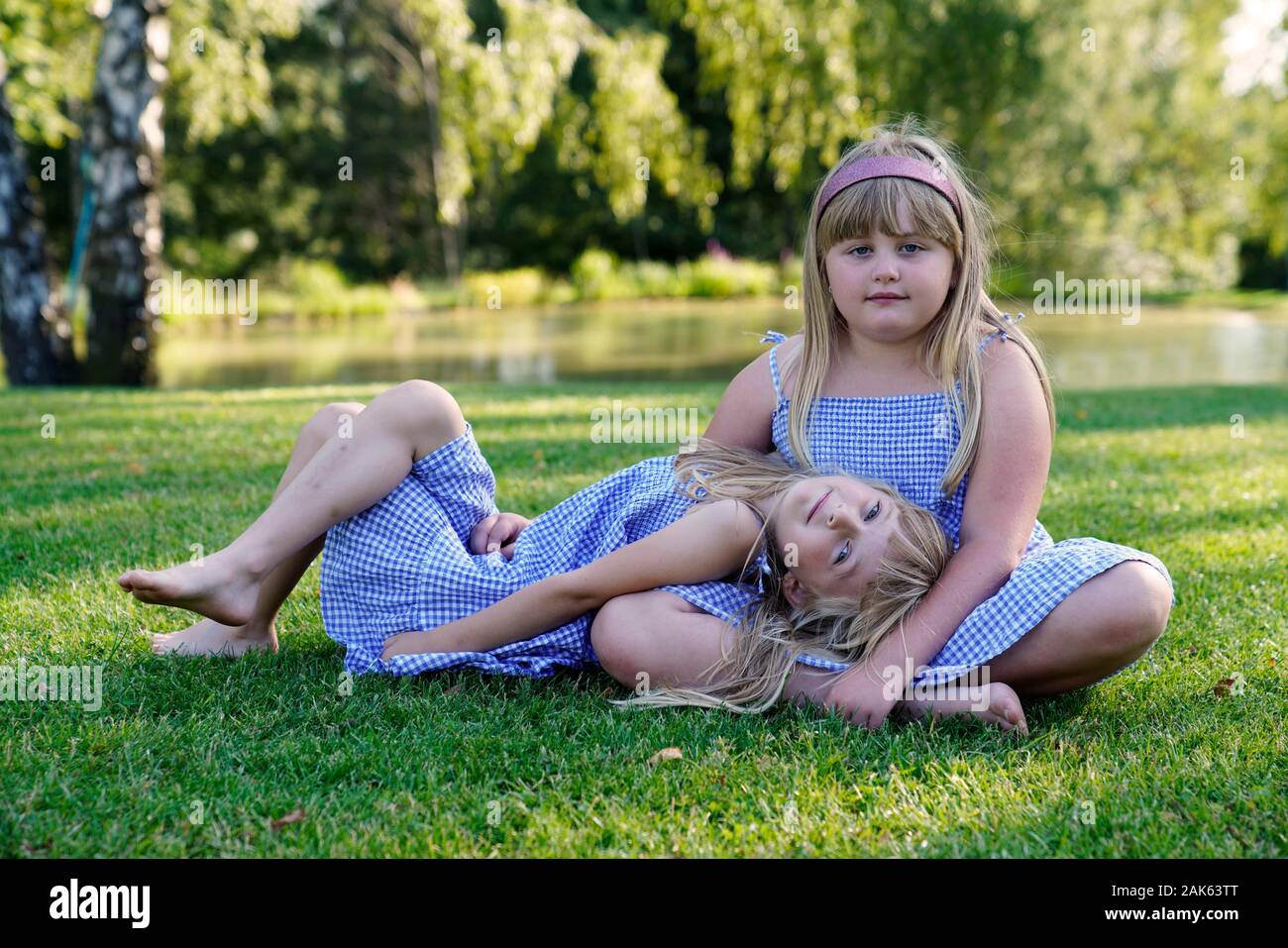 Zwei Mädchen, Geschwister sitzen auf der Wiese, 6 und 7 Jahren, Porträt, Tschechische Republik Stockfoto
