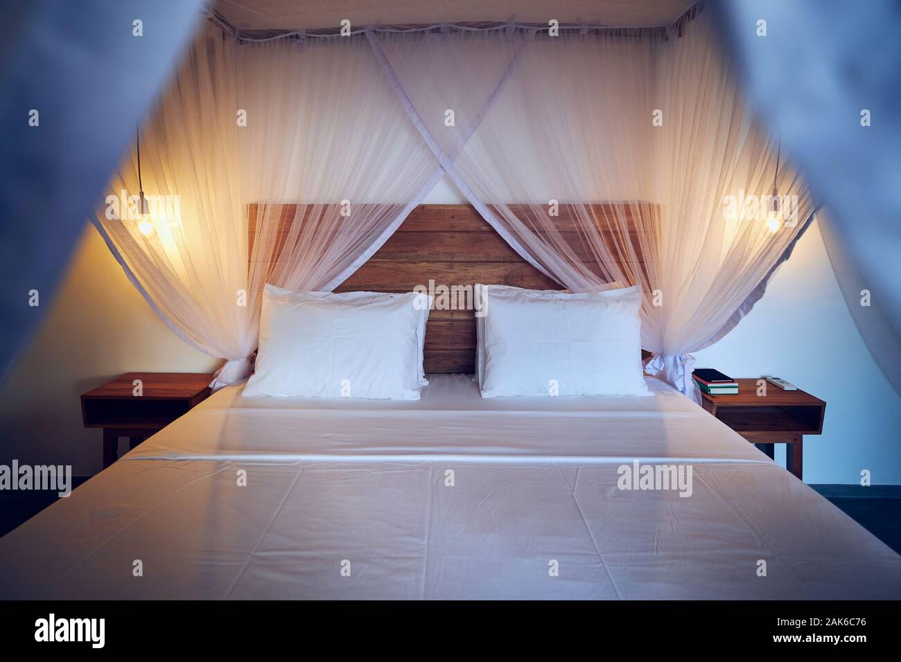 Luxuriöse Unterkunft in tropischen Ziel. Doppelbett mit Moskitonetz in moderne Bungalow. Stockfoto