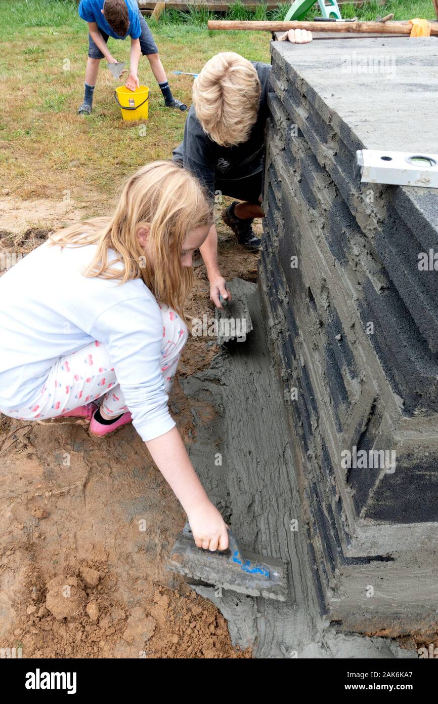 Schwester und Bruder finishing Zement arbeiten für eine Feuerstelle. Zawady Gmina Rzeczyca Polen Stockfoto