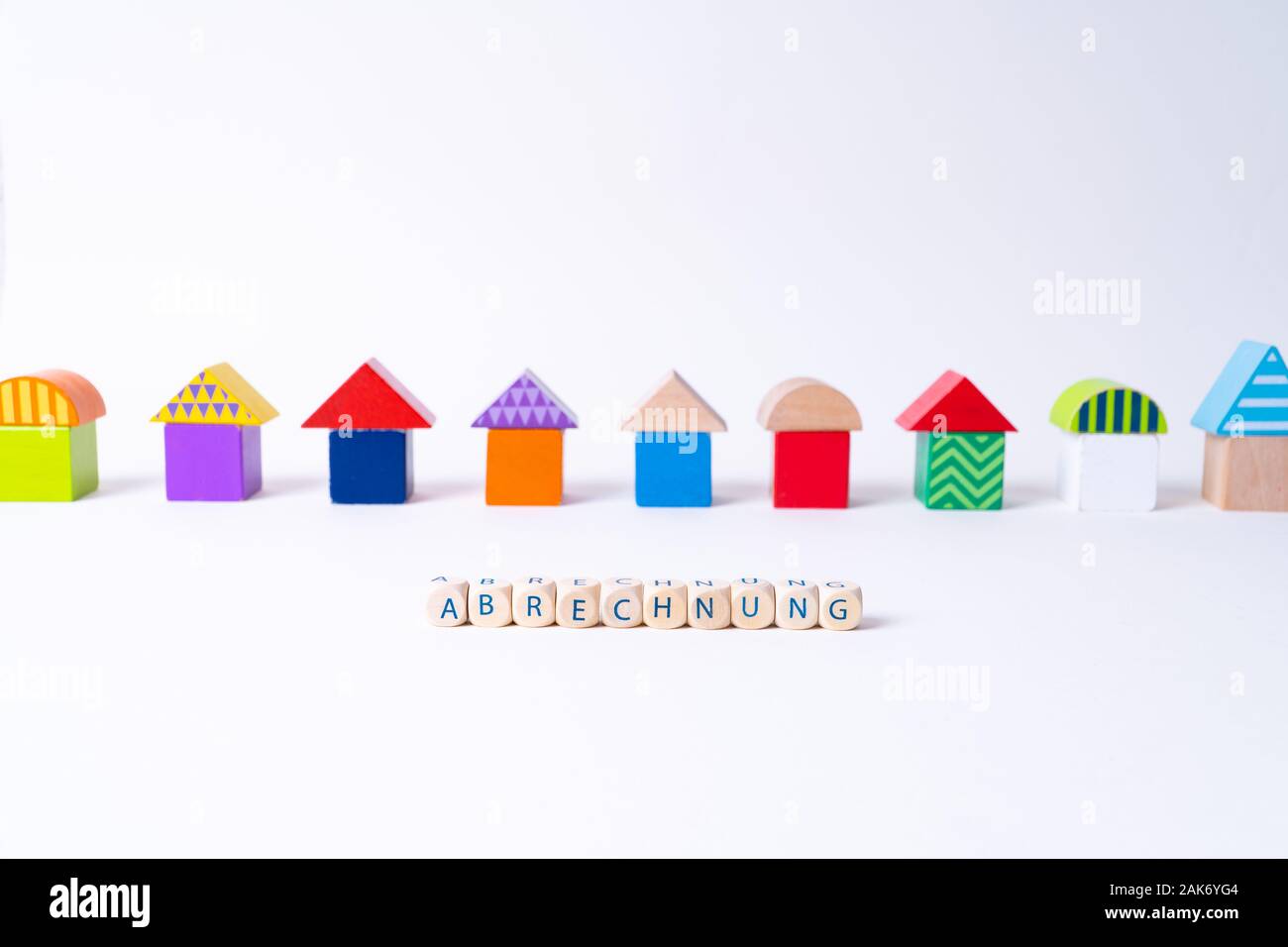 Würfel mit Buchstaben: "Abrechnung", das deutsche Wort für Rechnung vor einer Reihe von Häusern gebaut von bunten Spielzeug Spielzeug Bausteine Stockfoto