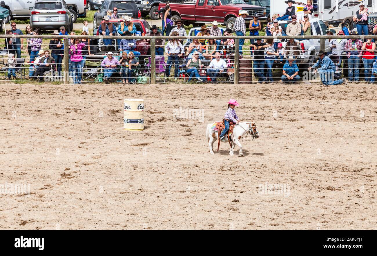 Ein junges Mädchen reitet ihr Pony rund um das Barrel Racing Kurs, beim Zuschauer verfolgen. Die jährlichen Memorial Day Wochenende Rodeo im Twisp, Washington, USA. Stockfoto