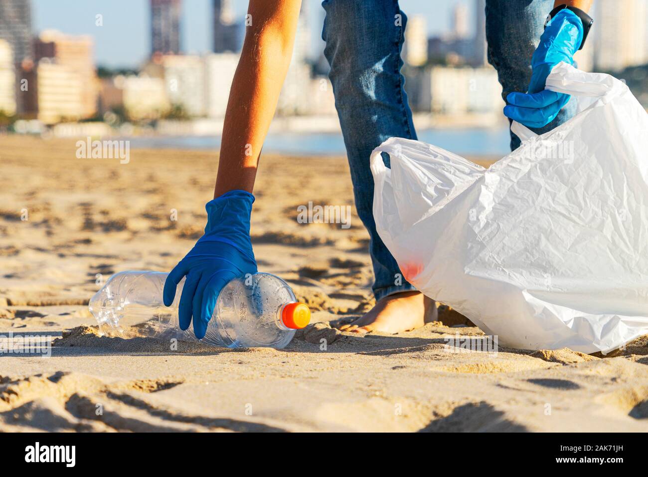 Sauberer Strand aus Kunststoff. Hand herauf Plastikflasche Papierkorb vom Strand und in Plastikbeutel für Recycling Stockfoto