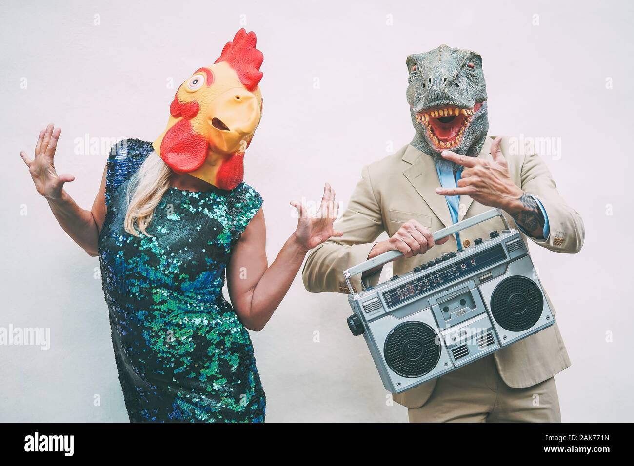 Crazy senior Paar tragen Huhn und T-rex Maske beim Tanzen Outdoor - Reife trendige Leute Spaß haben, Feiern und Musik hören Stockfoto