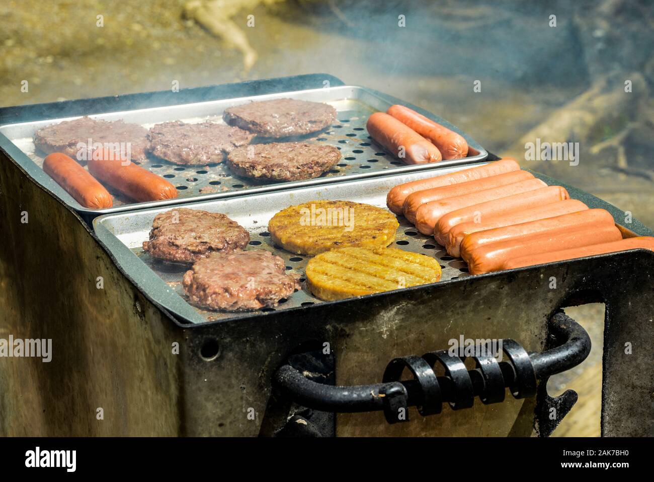 Horizontale Schuß von Hot Dogs und Burger vom Grill auf einen Grill im Freien. Stockfoto