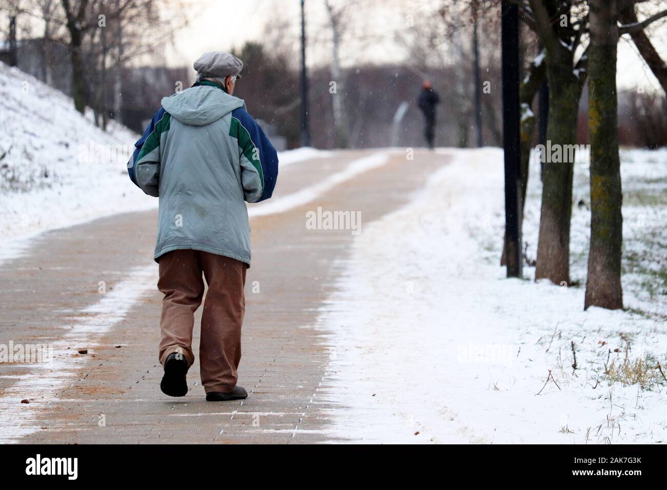 Ältere Mann zu Fuß auf die ländliche Straße während der Schnee. Konzept der Kälte, Winter, Armut Stockfoto