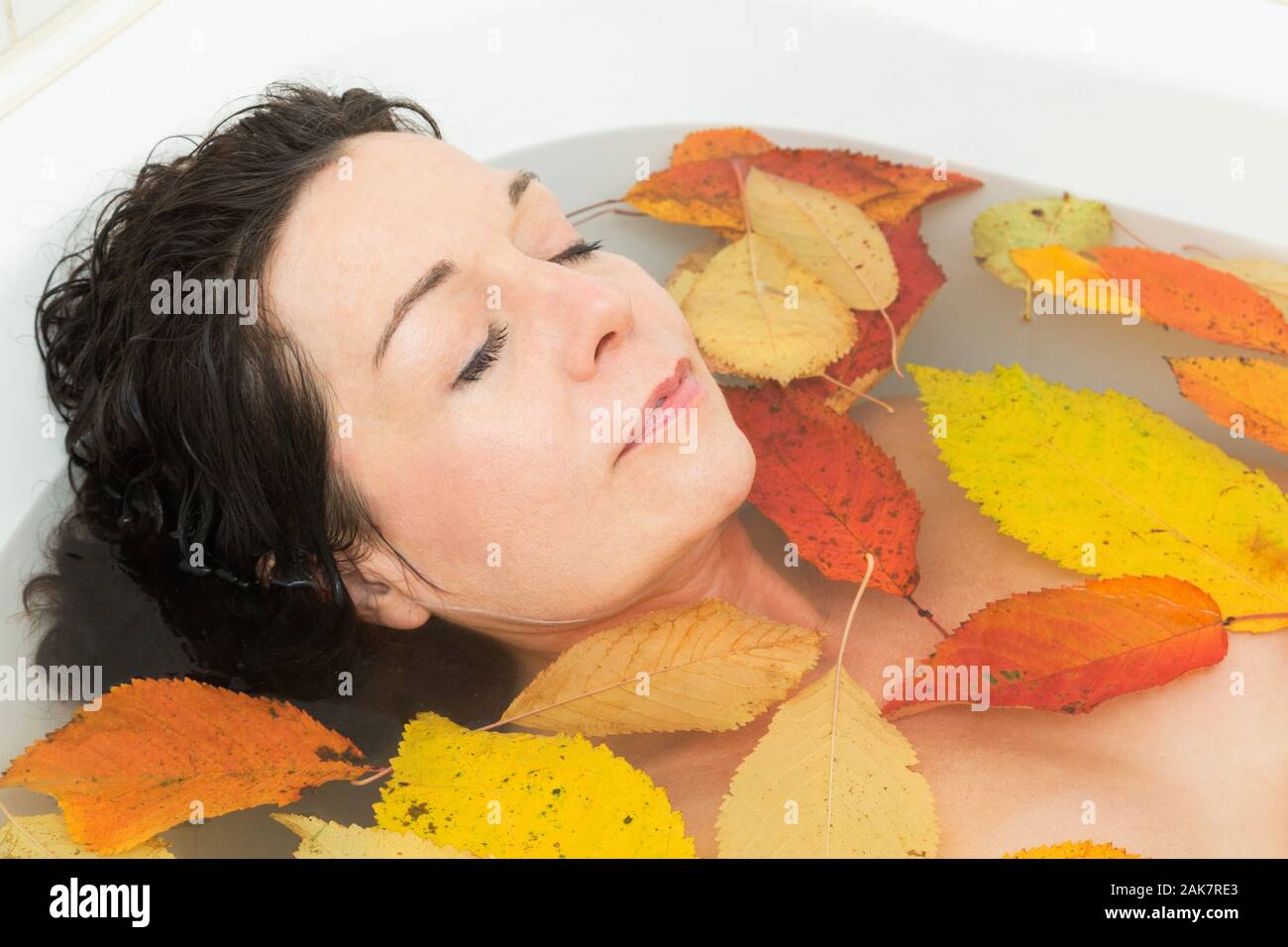 Frau baden mit Blätter im Herbst Stockfoto