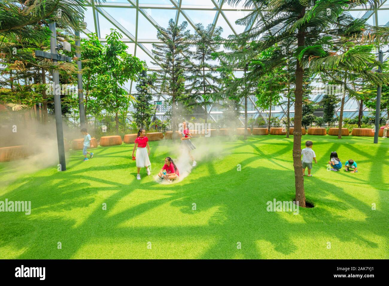 Singapur - Aug 8, 2019: lustige Kinder an nebligen Schalen, ein einfacher Spielplatz verfügt über schüsselförmige Plattformen mit künstlichem Rasen die Nebel lösen Stockfoto