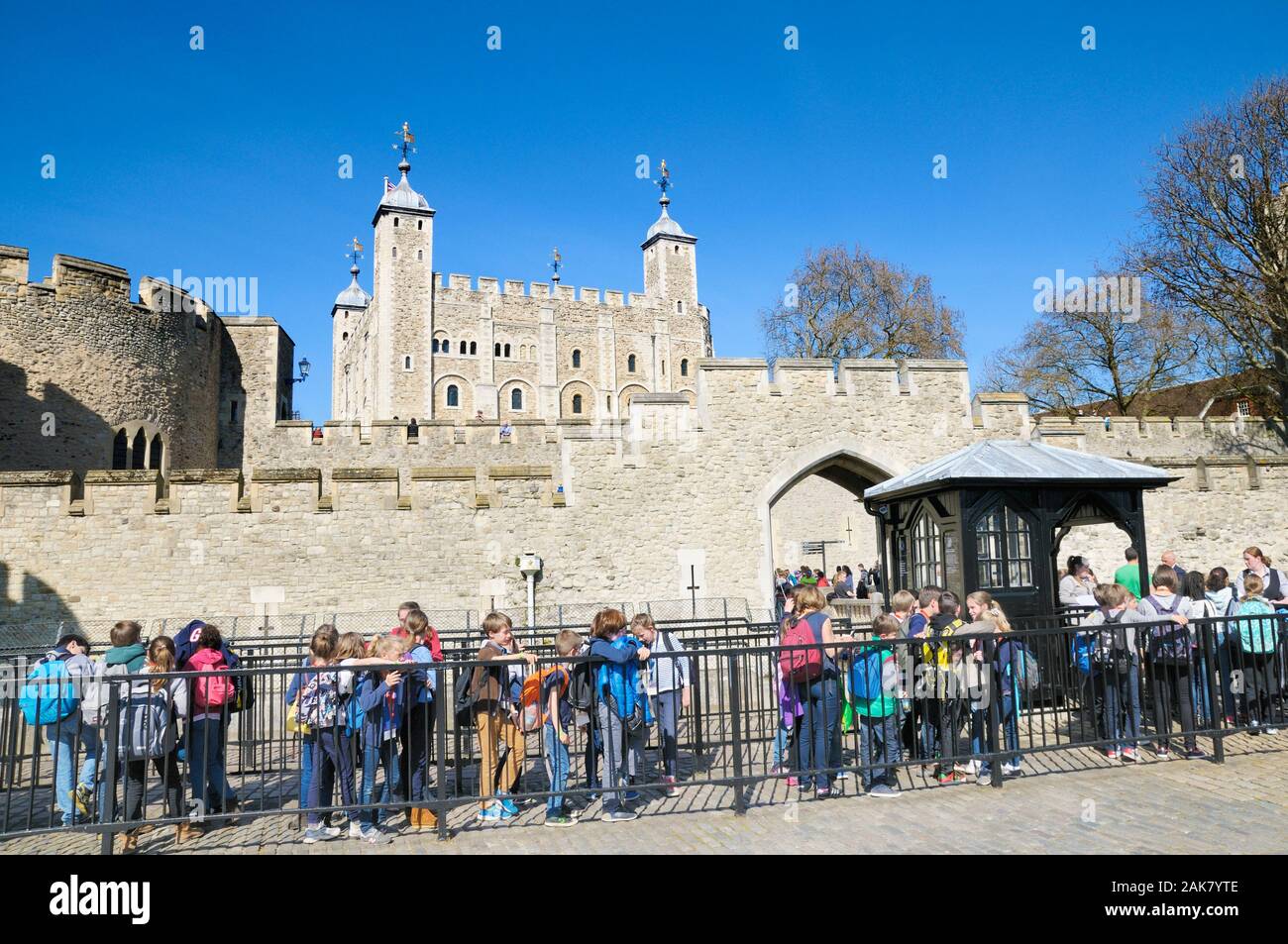 Schule Kinder queuing außerhalb der Mauern von Henry III watergate Eingang mit der berühmten Weißen Turm im Hintergrund, der Tower von London, England, Großbritannien Stockfoto