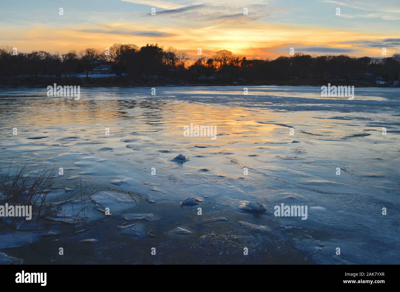 Ein winter Sonnenuntergang senkt sich über einen gefrorenen Hafen. Stockfoto