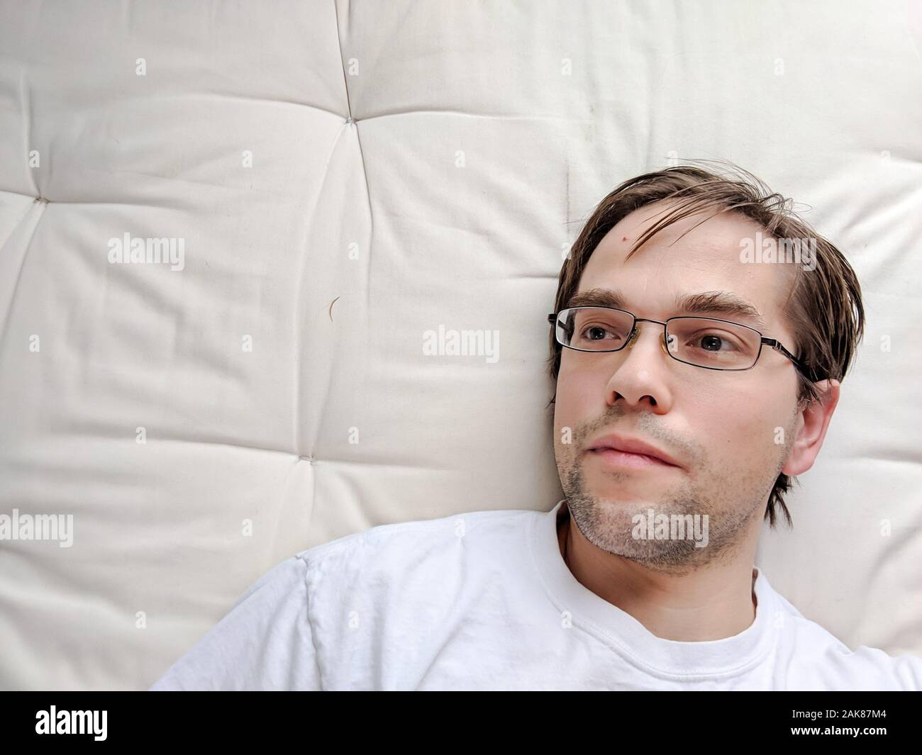 Junger Mann auf dem Bett liegend Stockfoto