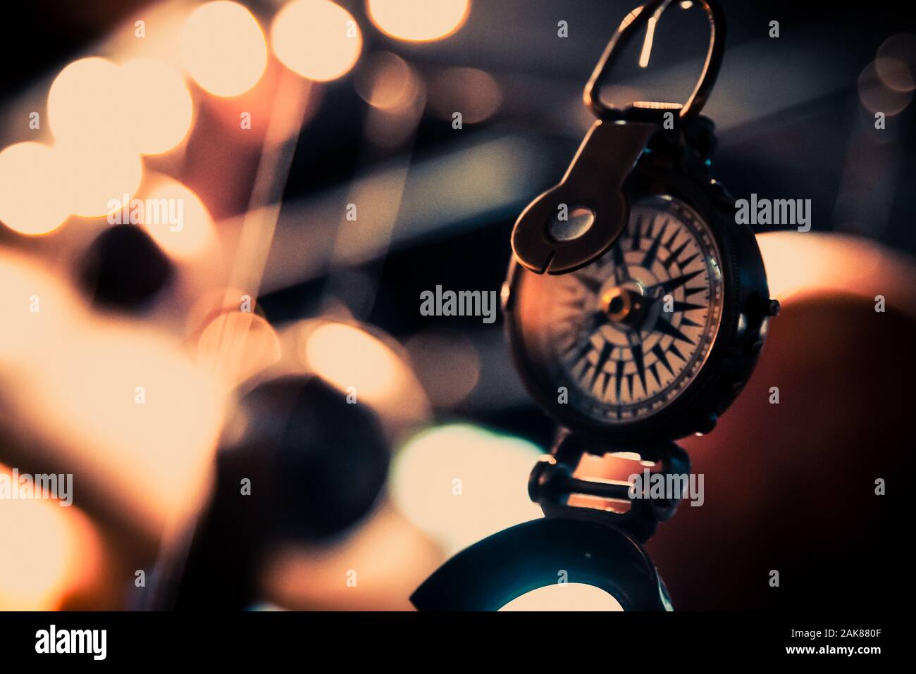 Schönes Bokeh eines Kompass hängen mit Lichtern und Überlegungen in den Hintergrund. Konzept verloren zu gehen, Freiheit und Streben nach Glück. Stockfoto