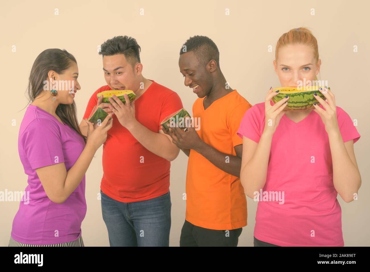 Studio shot von Happy teenage Mädchen mit vielfältigen Gruppe von multi-ethnische Freunde im wieder ein Lächeln beim Essen ein Stück Wassermelone zusammen Stockfoto