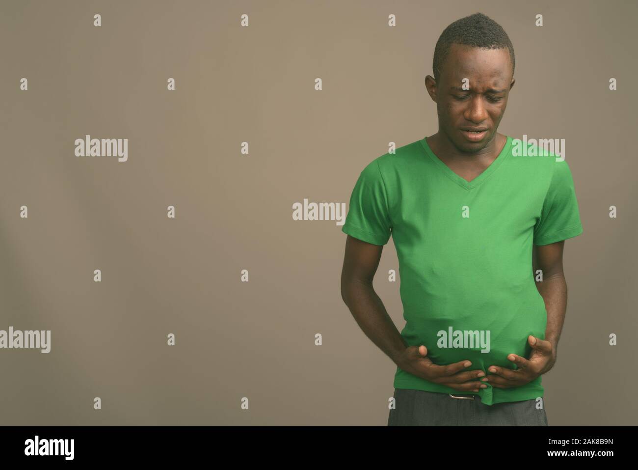 Junge afrikanische Mann, grünes T-Shirt gegen grauer Hintergrund Stockfoto