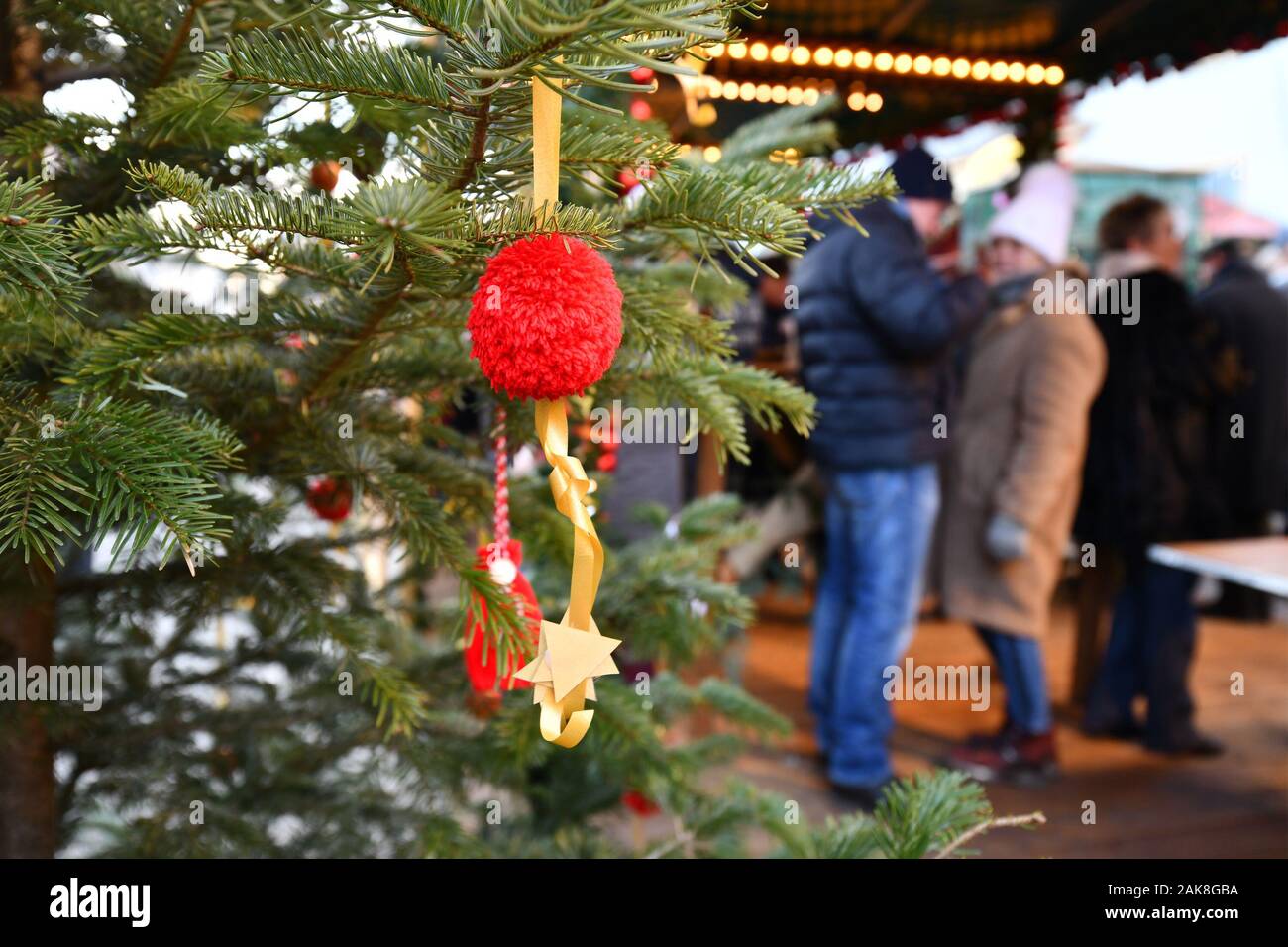 Rot Christbaumschmuck Christbaumkugel mit Verkaufsstand und Menschen in verschwommenen Hintergrund auf traditionellen Deutschen Weihnachtsmarkt Stockfoto