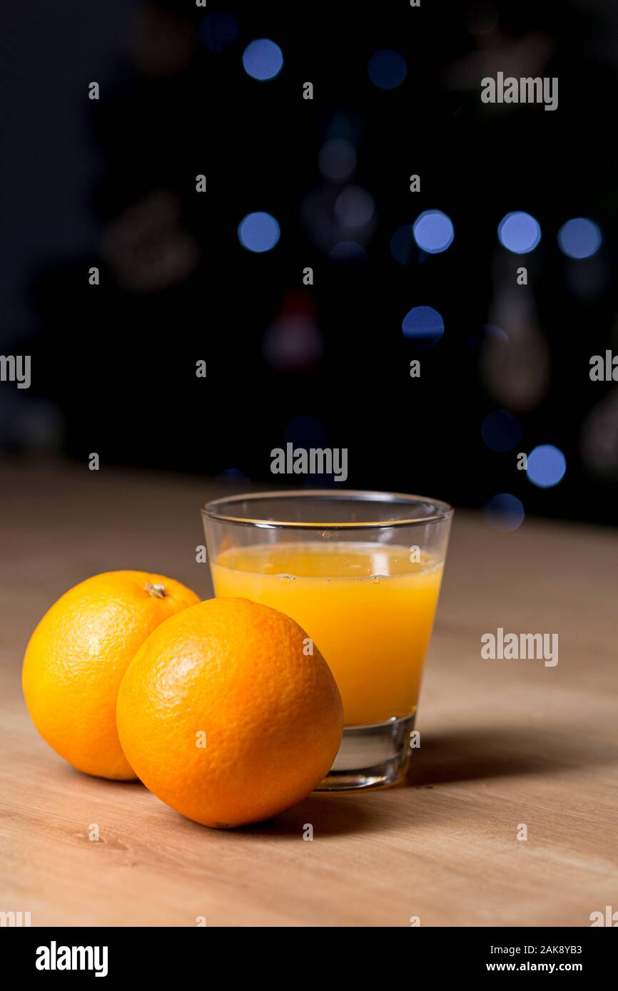 Orangensaft auf ein Trinkglas mit frischen Orangen Obst auf einem Holztisch Stockfoto