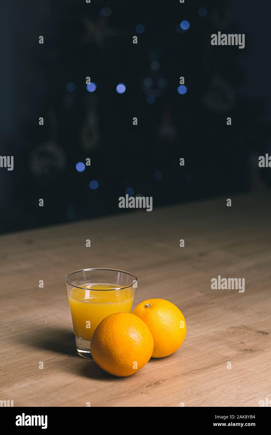 Orangensaft auf ein Trinkglas mit frischen Orangen Obst auf einem Holztisch Stockfoto