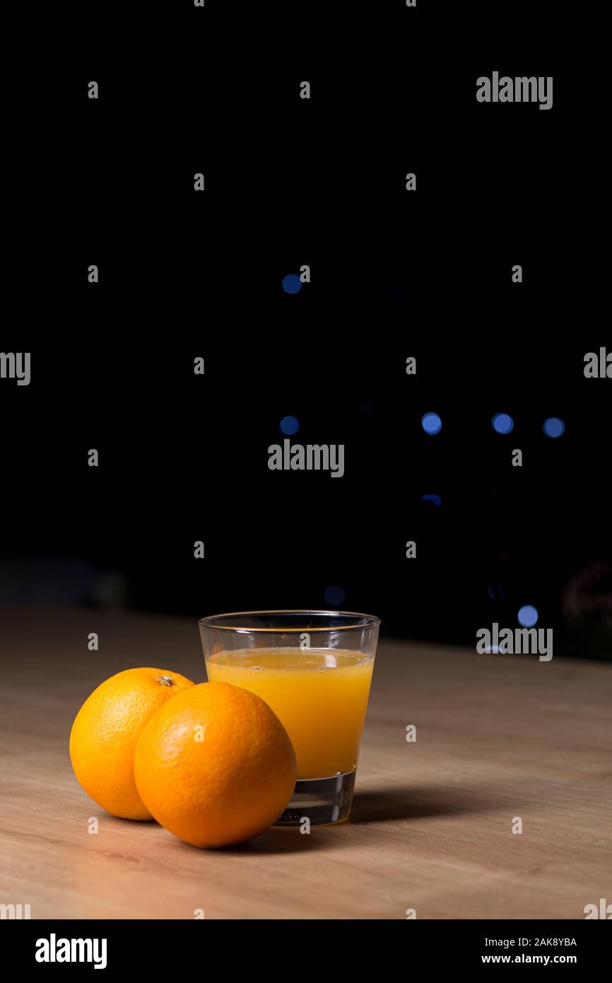 Orangensaft auf ein Trinkglas mit frischen Orangen Obst auf einem Holztisch Stockfoto