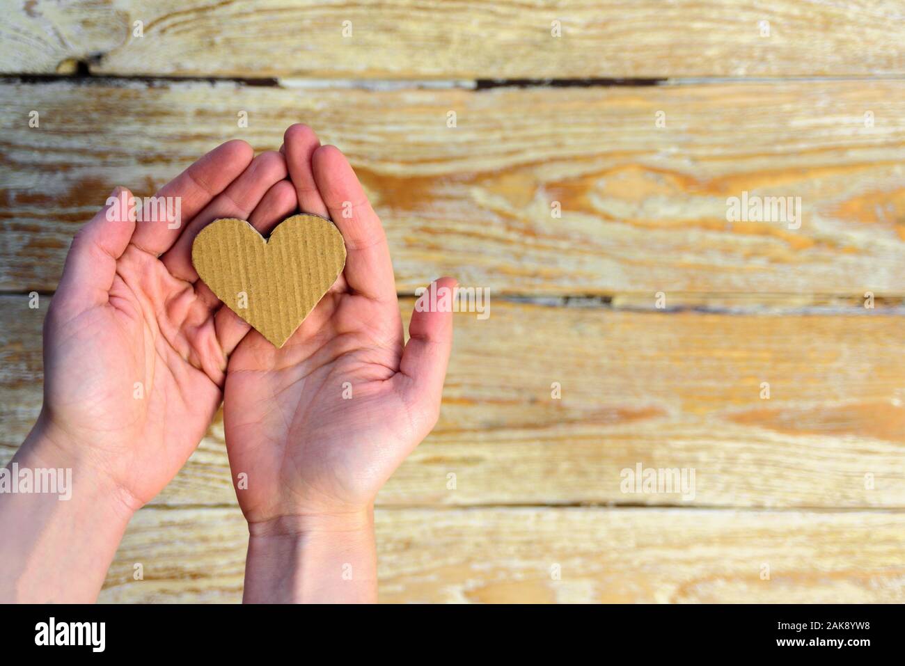 Karton Herz in Frau Hände. Nachhaltige Karte für Valentines Tag. Wiederverwendung Konzept Stockfoto