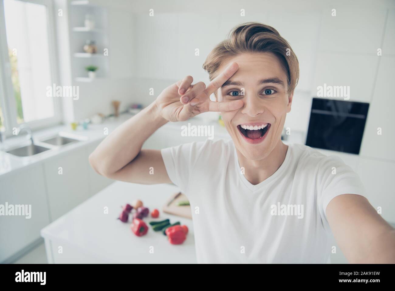 Self-portrait Seiner er schöne attraktive Heiter froh gelaunt optimistisch funky Kerl mit v-sign Spaß an Licht, weißes, modernes Interieur Hotel Stockfoto