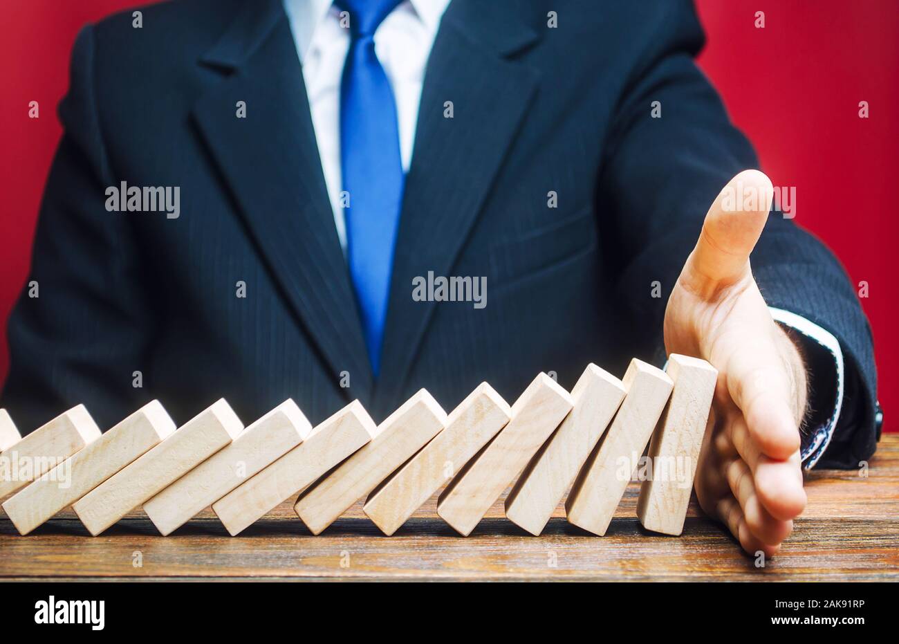 Geschäftsmann stoppt Domino fällt mit seiner Handfläche. Risk Management Konzept. Erfolgreiche Unternehmen und Problemlösung. Stoppen Sie den zerstörerischen Processe Stockfoto