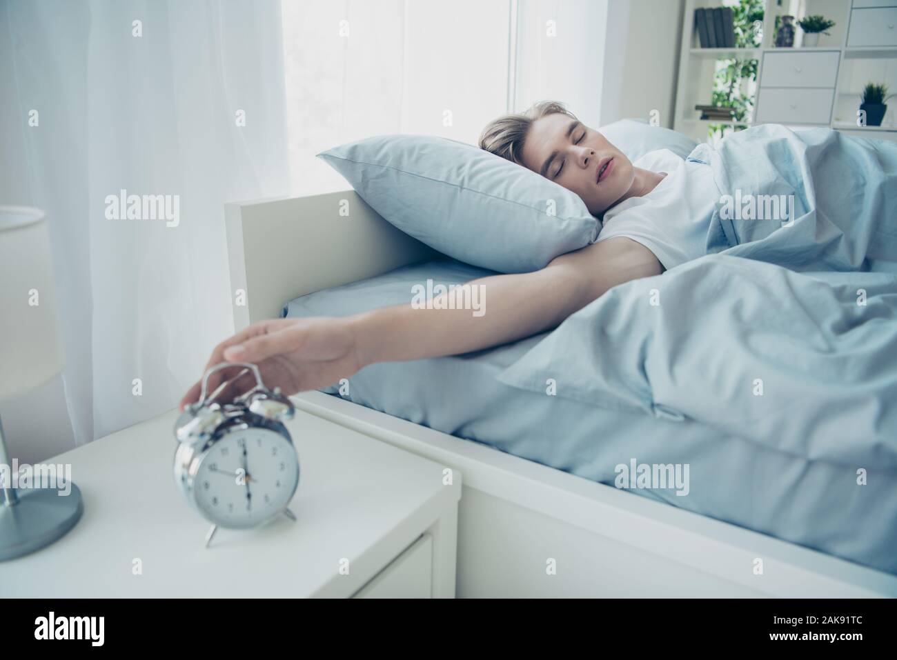 Portrait von Verträumten müde verschlafen blondes Haar Mann liegend auf Bett schlafen schwieriger Tag gestern Ignorieren klingeln Bell im Haus drinnen Stockfoto
