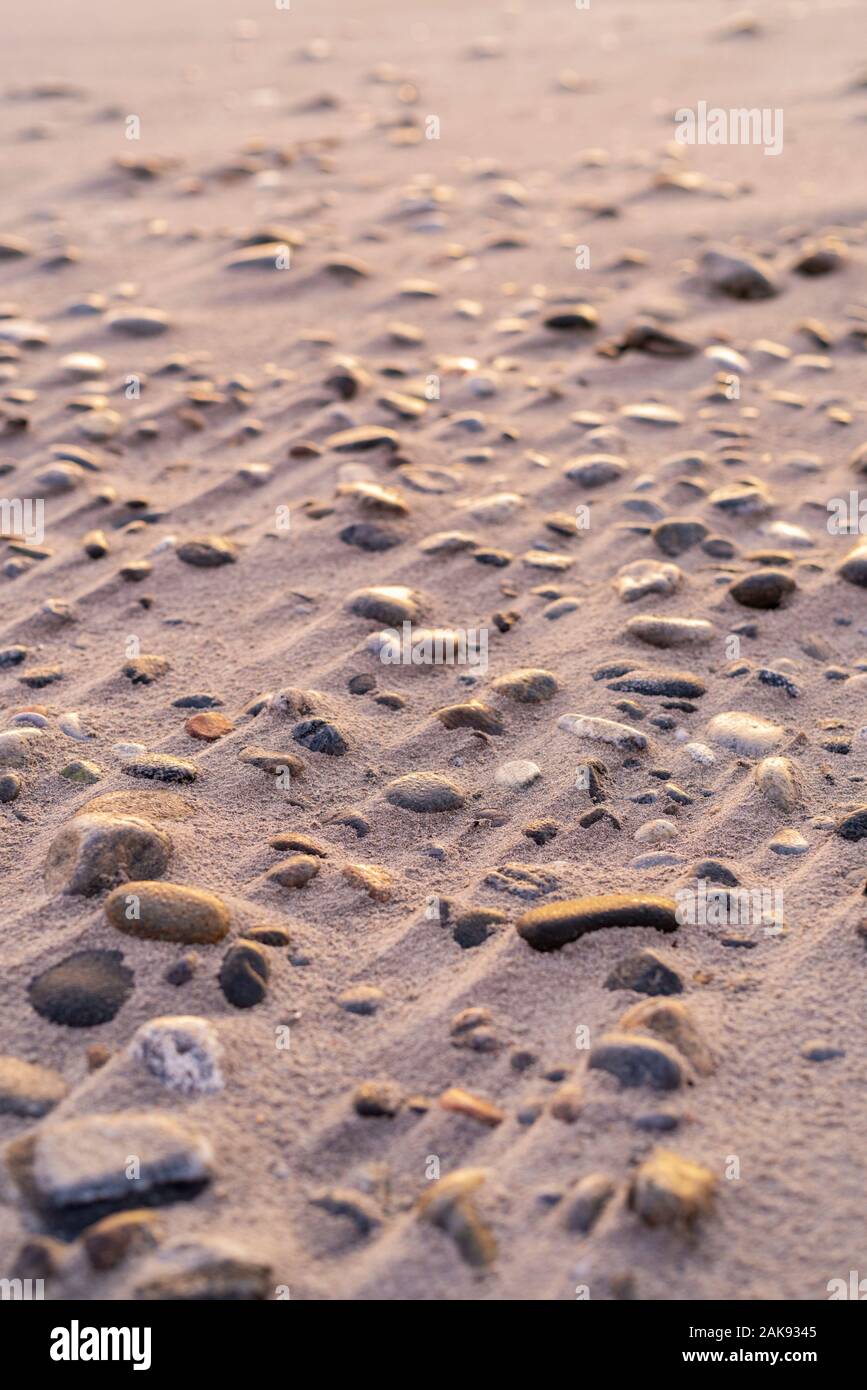 Voller Rahmen aus kleinen Kieselsteinen und Steinen ein windgeblasener Sandstrand Stockfoto