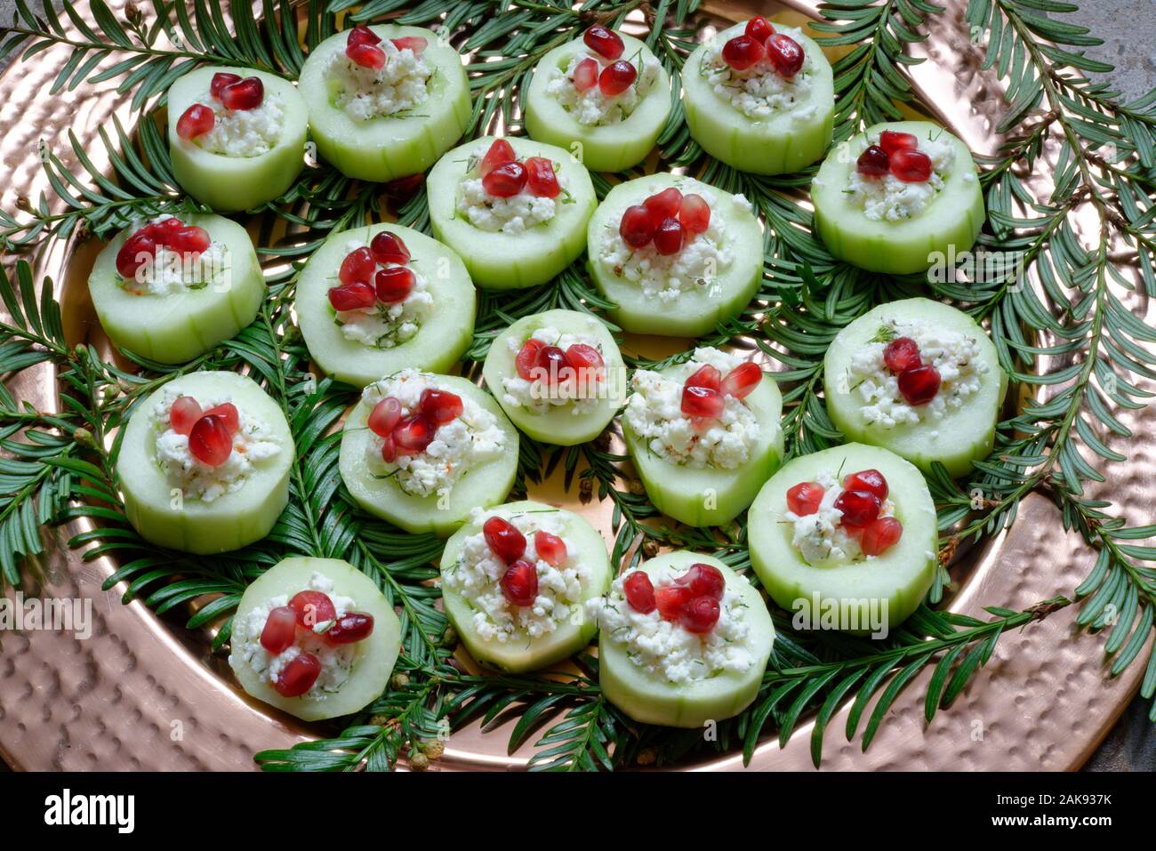 Weihnachtsfeier Essen, kleine auf einer Servierplatte isst mit Weihnachten immergrüne Pflanze Dekoration serviert. Gurke und Käse Mischung mit Granatapfel Samen. Stockfoto