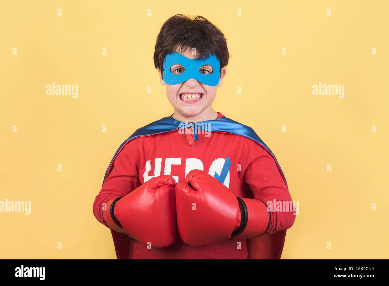 Superhelden, Portrait eines Jungen in Superhelden Kostüm auf gelbem Hintergrund Stockfoto