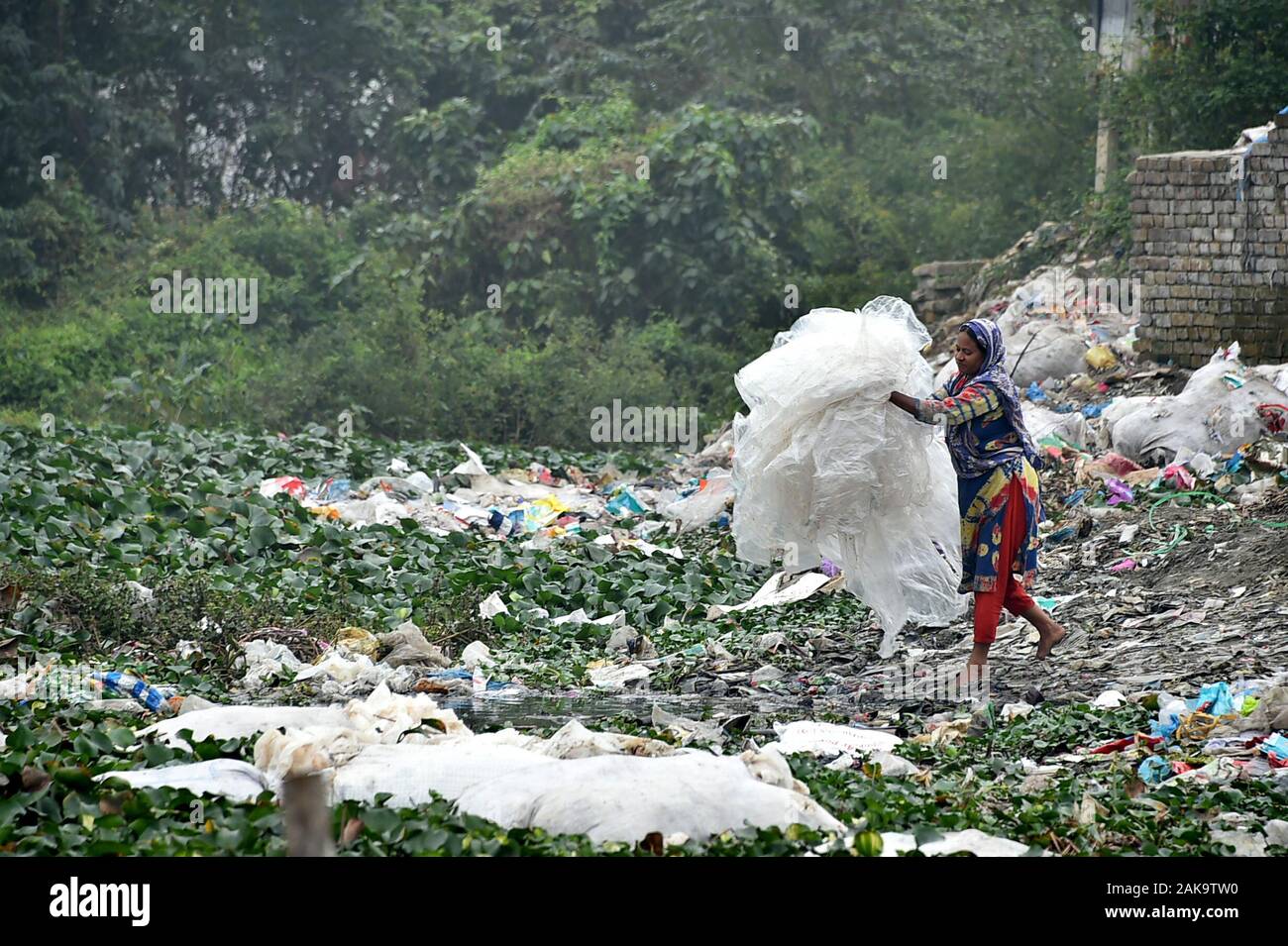 Dhaka. 8 Jan, 2020. Eine Frau trägt Kunststoffabfälle an einem Dumping site in Dhaka, Bangladesch auf Jan. 8, 2020. Ein hohes Gericht Abteilung Bank in Bangladesch hat die betroffenen Behörden mit Kunststoffprodukten in Küstengebieten und Hotels, Motels und Restaurants im ganzen Land innerhalb der nächsten ein Jahr zu verbieten. Credit: Str/Xinhua/Alamy leben Nachrichten Stockfoto