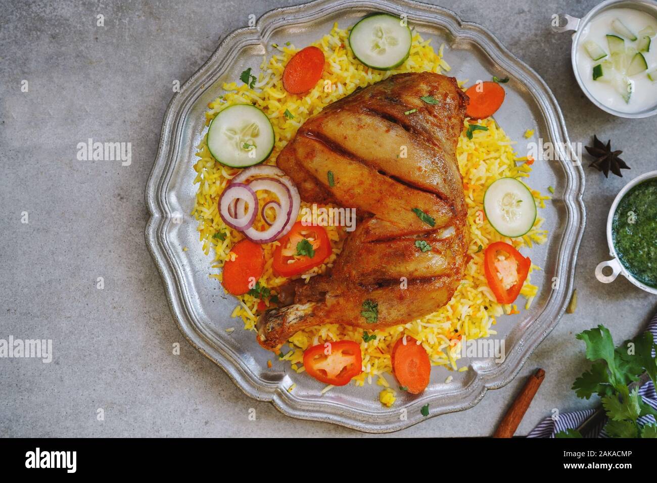 Huhn Kabsa/kuzhi Mandhi oder Mandi Biryani serviert mit Joghurt Minze Chutney Stockfoto
