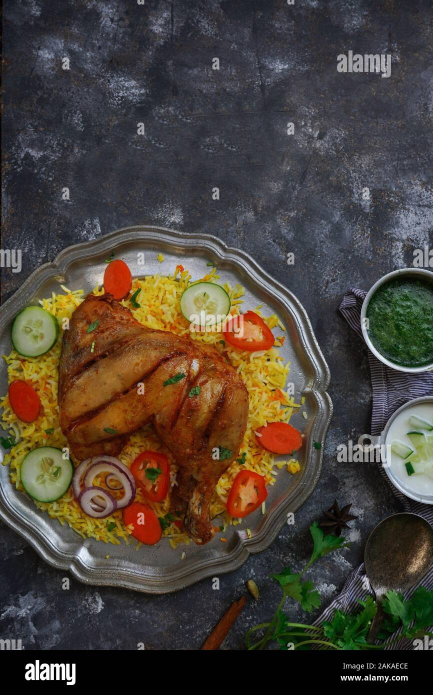 Huhn Kabsa/kuzhi Mandhi oder Mandi Biryani serviert mit Joghurt Minze Chutney Stockfoto