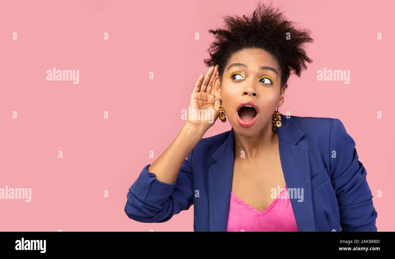 Klatsch Konzept. Afro Frau legt Hand an ihr Ohr zu hören besser, hören etwas über rosa Hintergrund, freier Speicherplatz Stockfoto