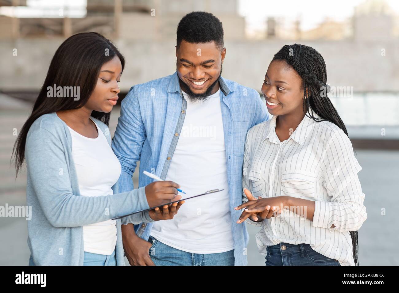 Beziehung Fragen für Paare. Afro Frau bittet jungen Eheleuten eine Umfrage auf der Straße, Befragungen im Freien Stockfoto