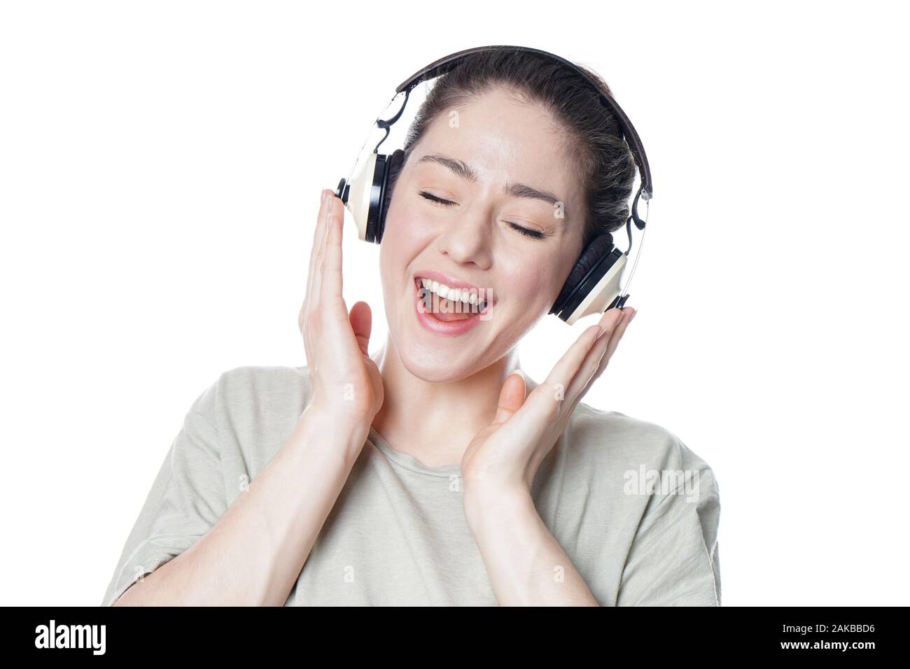 Glückliche junge Frau mit Kopfhörern Singen mit Musik mit geschlossenen Augen - auf weißem Hintergrund Stockfoto