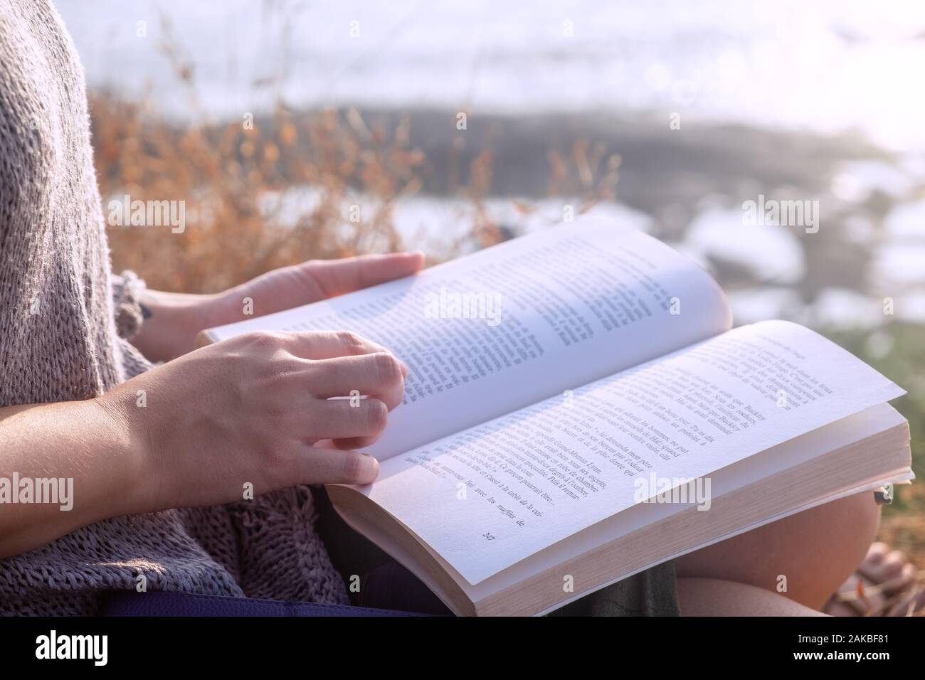 Junge Frau mit Buch beim Sitzen im Freien, Nahaufnahme Stockfoto